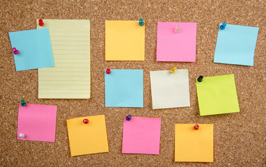blank sticky notes on cork board with pins 