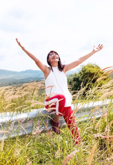Fototapeta premium The beautiful woman raised hands up in the air and breathing,with smile and happy feeling,enjoy with fresh air,on holiday,in a park,blurry light around