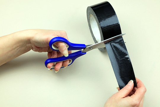 Using A Pair Of Scissors To Cut Duct Tape