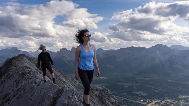 Time Lapse. Adventurous Girl is hiking up a rocky mountain during a cloudy and rainy day. Taken from Mt Lady MacDonald, Canmore, Alberta, Canada. Concept: Adventure, Travel, Hike