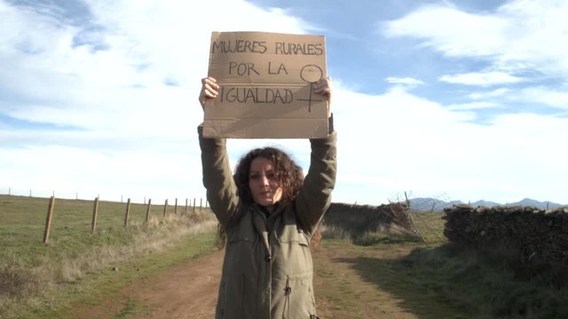 Feminist woman in a rural area of Spain with a banner in Spanish that says: rural women for equality. Concept: feminism, women's day, equality