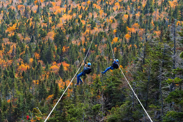 two people sliding down very long and fast zipline during autumn in Stowe, Vermont