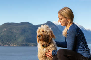 Adventurous Girl Hiking on top of a Mountain with a dog during a colorful sunset. Taken on Tunnel Bluffs Hike, near Vancouver and Squamish, British Columbia, Canada.