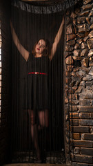 Fototapeta na wymiar Seduce, girl behind curtains of black threads.