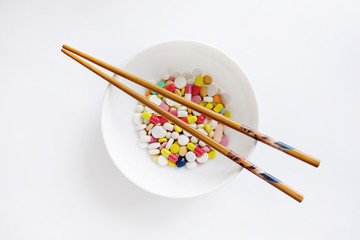 Fototapeta na wymiar Variety of pills on a plate with Chinese sticks isolated on white