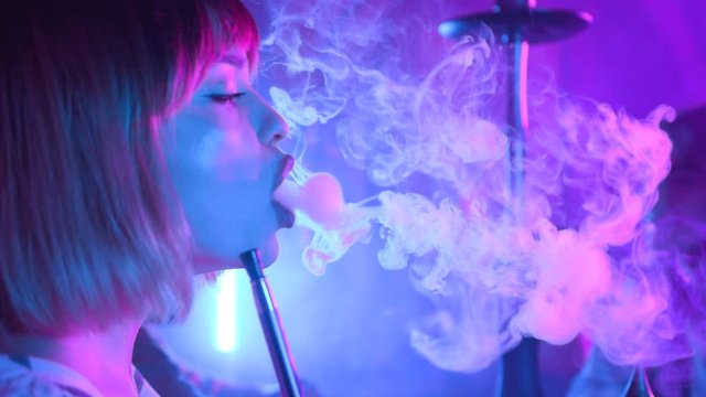 Close up woman talking enjoying hookah at the bar feel happy young friendship communicate emotion shisha smoker male lounge handsome female vape beautiful attractive company relax slow motion