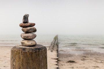 Steintürmchen auf einer Buhne am Strand an einem grauen Tag