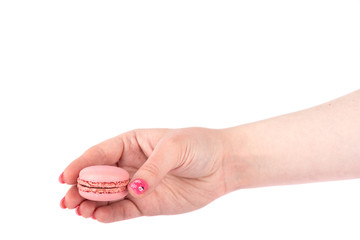 Tasty pink macaroon in female hand isolated on white.