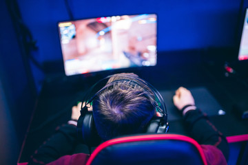 Professional gamer playing online games tournaments pc computer with headphones, Blurred red and blue background © Parilov