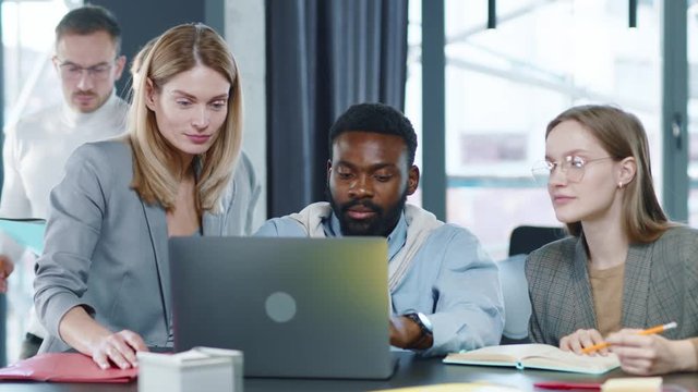 Young multi-ethnic co-workers gathered together working discuss current issues common tasks african team leader talk with colleague business workplace skilled technology strategy slow motion