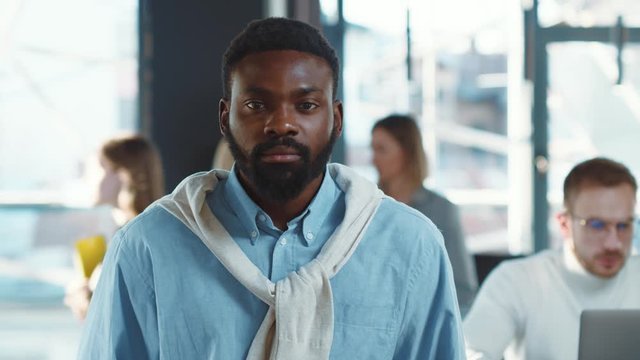 Serious young african american man portrait ooking at camera standing in office new business owner standing confidently feeling good emotions training work startup beard close up slow motion