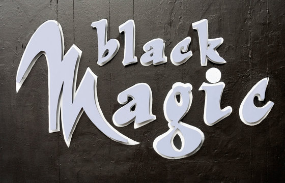 BLACK MAGIC sign mounted on black building wall.