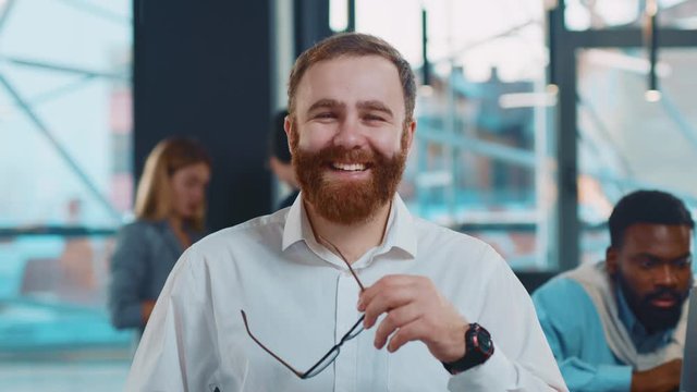 Happy young man team leader with smiling face posing in office confident business executive ceo looking at camera startup founder portrait training work startup success successful beard close up slow