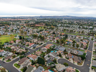 Aerial view of urban sprawl. Suburban packed homes neighborhood with road.during clouded day. Vast...