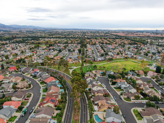 Aerial view of urban sprawl. Suburban packed homes neighborhood with road.during clouded day. Vast subdivision in Irvine, California, USA