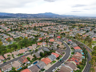 Aerial view of urban sprawl. Suburban packed homes neighborhood with road.during clouded day. Vast subdivision in Irvine, California, USA