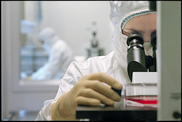 Technician looking into microscope in laboratory