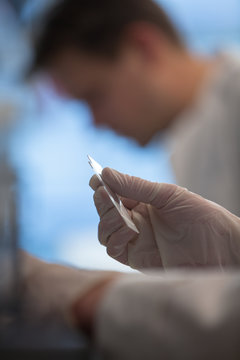 Cropped image of scientist by colleague holding samples at laboratory