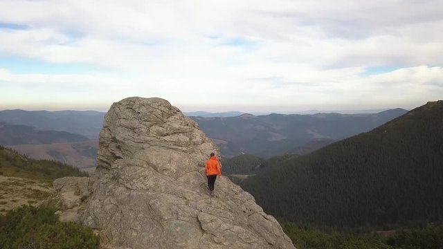 Aerial view of a hiker man climbing big rock in mountains.