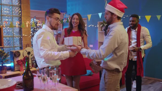 Happy diverse young people arriving to their friend's house making a suprise loading with Christmas gifts and greetings celebrating party holiday together.