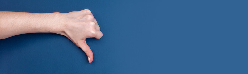 Female hand shows thumb down on blue background, banner format, place for text
