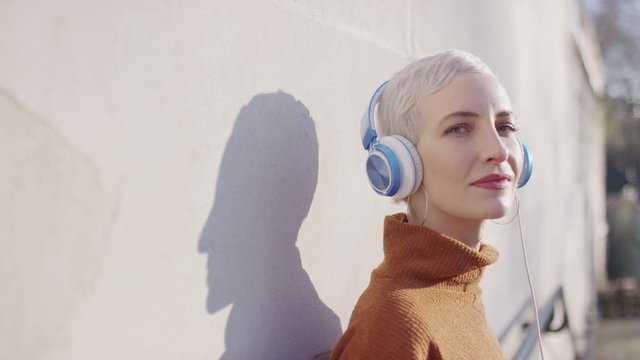 Portrait of young female in headphones turning and smiling to camera, in slow motion
