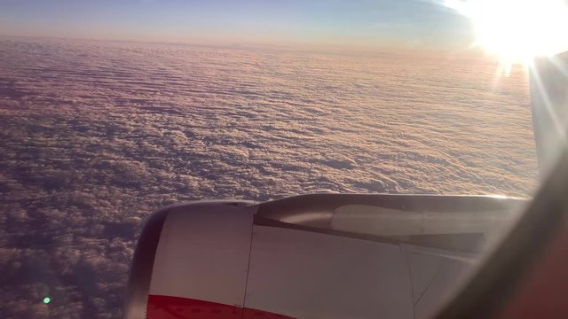 Cinematic view of airplane motor above the calm clouds at sunset - modern transportation in business economy first class POV