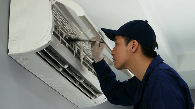 technician service using brush to cleaning the air conditioner indoors