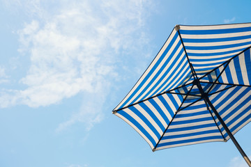 blue striped beach umbrella with sky background