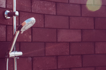 Shower head on red-brown brick walls for outdoor showers. Vintage shower head.