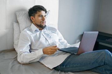 man sitting on sofa and working on laptop