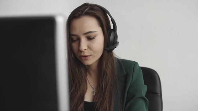 Young Brunette woman service operator calls in office. Young customer support manager consulting consumer by headset answering questions. Smiling business woman customer support agent.