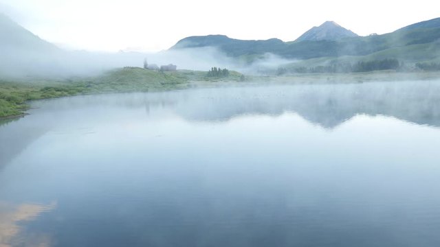 Crested Butte foggy lake sunrise low aerial and mountains panning right GH4