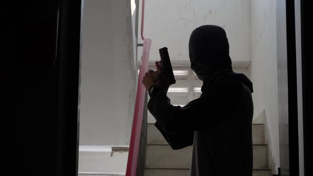Silhouette of cruel killer in black clothes shooting witness with pistol, contract murder,  revenge
