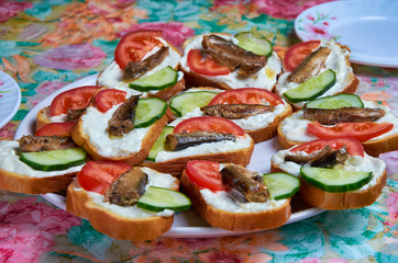 Tasty sandwiches with mayonnaise, tomato, cucumber, sprats. canned fish on a dish close-up.