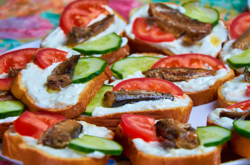 Tasty sandwiches with mayonnaise, tomato, cucumber, sprats. canned fish on a dish close-up.