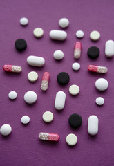 Pills and capsules on purple background from above. Various Pills.