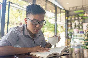 Asian man drinking coffee and reading books