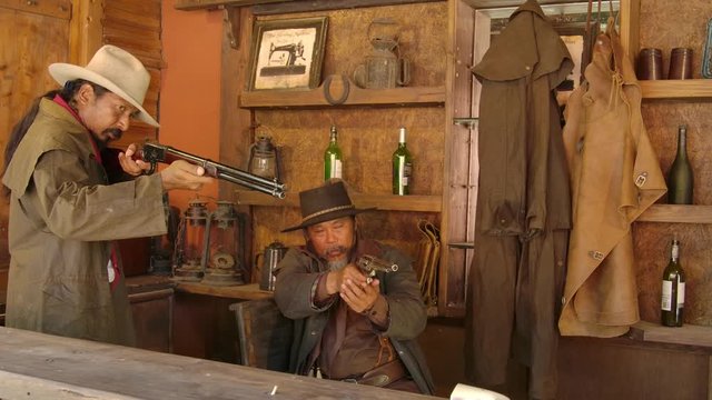 Two Asian cowboys shooting rifle and revolver gun in the couter saloon whisky bar and point the weapon left and right.