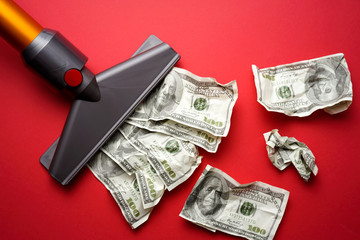 vacuum cleaner nozzle sucking money dollar bill on red background