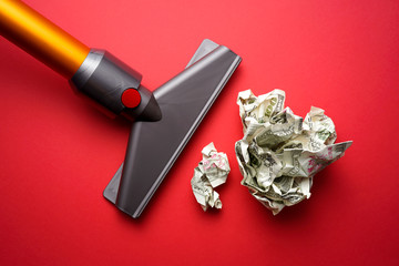 vacuum cleaner nozzle sucking money dollar bill on red background