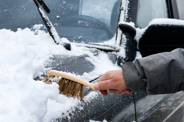 A man is removing snow from the car.