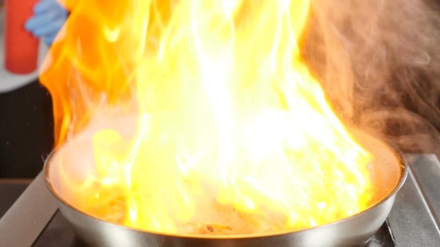 Close-up footage of chef cooking main banquet dish. Preparing tiger shrimps with fire in slow motion. flambe style dish on pan in hotel restaurant. Meal preparation concept. hd video