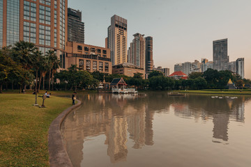 Lake and modern buildings on Sukhumvit Road at sunset, at Benchasiri Park, in Bangkok, Thailand