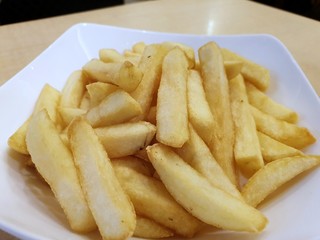 Selective focus of french fries in white bowl on wooden table, ready to eat or serve, fast food restaurant