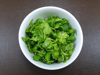 Top view of fresh coriander leaf in white bowl on wooden table as a background, for making cooking, healthy food concept