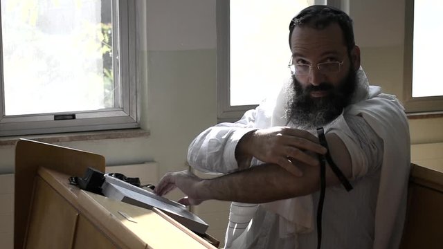Jewish prayer. Ashkenazi synagogue. Orthodox Jew, with tefillin and tallit, holds up a Sefer Torah.