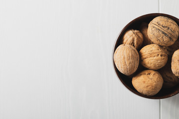 Walnuts on a white table in a small wooden plate, place for an inscription