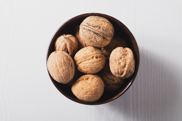 Walnuts on a white table in a small wooden plate