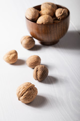 Side view of walnuts on a white table in a small wooden plate